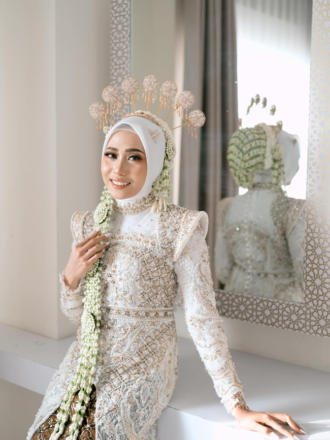Dalam foto yang diunggah, Rizky Ridho mengenakan basofi dan peci serba putih yang dipadukan dengan Batik juga kalung melati. Sedangkan Sendy Aulia tampak memakai gaun kebaya putih dengan detail bebatuan emas juga kain Batik yang serasi dengan suaminya. Foto: Instagram @rizkyridhoramadhani