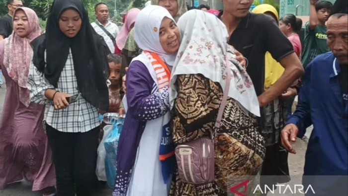 Seorang haji yang tergabung dalam Kloter 33 asal Kabupaten Jember disambut keluarganya yang datang menjemput di Asrama Haji Debarkasi Surabaya, Minggu (22/6/2025). ANTARA/Hanif Nashrullah