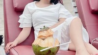 Momennya saat nongkrong di pinggir pantai ini tak kalah mencuri perhatian. Ia tampak memesan air kelapa di batok kelapa utuh Foto: Instagram @putriisnari