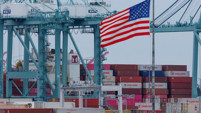 FILE PHOTO: A U.S. flag flutters near shipping containers as a ship is unloaded at the Port of Los Angeles, in San Pedro, California, U.S., May 1, 2025. REUTERS/Mike Blake/File Photo