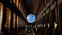 Trinity College Library, Irlandia. Salah satu perpustakaan terindah di dunia dengan desain abad ke-18. Rumah bagi Book of Kells, manuskrip kuno yang sangat berharga. Rak kayu tinggi dan koridor penuh buku menciptakan suasana magis. Mairo Cinquetti/NurPhoto via Getty Images