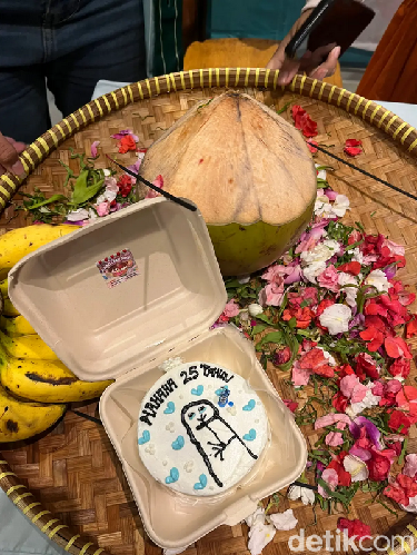 Wanita ini dan teman-temannya memberikan kue dalam bentuk sajen untuk temannya yang sedang berulang tahun.