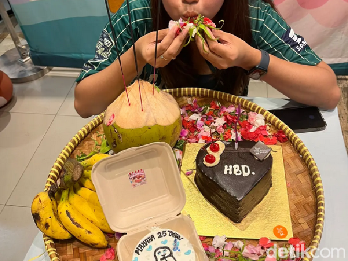 Wanita ini dan teman-temannya memberikan kue dalam bentuk sajen untuk temannya yang sedang berulang tahun.