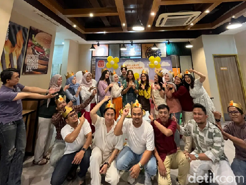 Wanita ini dan teman-temannya memberikan kue dalam bentuk sajen untuk temannya yang sedang berulang tahun.