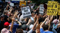 Mereka membawa poster bertuliskan “No War on Iran” dan “Trumo is a War Criminal menolak keterlibatan militer AS di Timur Tengah. (REUTERS/Caitlin Ochs)  