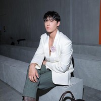 Kekasih Lim Ji Yeon itu memakai blazer putih tanpa dalaman, dengan paduan celana hijau garis-garis dan sepatu boots. Penampilannya dilengkapi dengan koleksi tas Prada dan hiasan bros bunga di dada kirinya. Foto: Getty Images