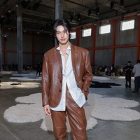 Dengan postur tubuh bak model, Win Metawin tampil karismatik memakai setelan kulit berwarna coklat. Di baliknya, Win memakai kemeja biru menerawang yang terbuka. Foto: Getty Images