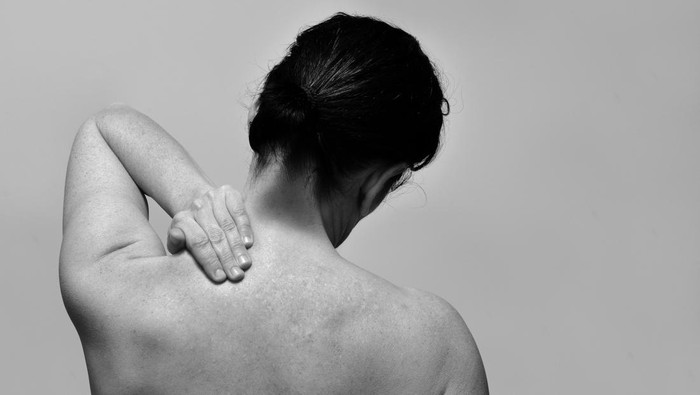 middle-aged woman with pain in the upper part of the spine