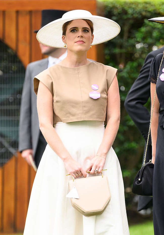 Eugenie melengkapi penampilannya dengan topi lebar khas Royal Ascot, yang mengingatkan banyak orang pada gaya ikonik film My Fair Lady. Ia juga mengenakan sepatu hak tinggi ramping dan membawa tas tangan favoritnya dari merek M2 Malletier, tas berbentuk heksagonal dengan sentuhan hardware emas dan tali rantai yang bisa dilepas. Foto: Getty Images/Max Mumby/Indigo