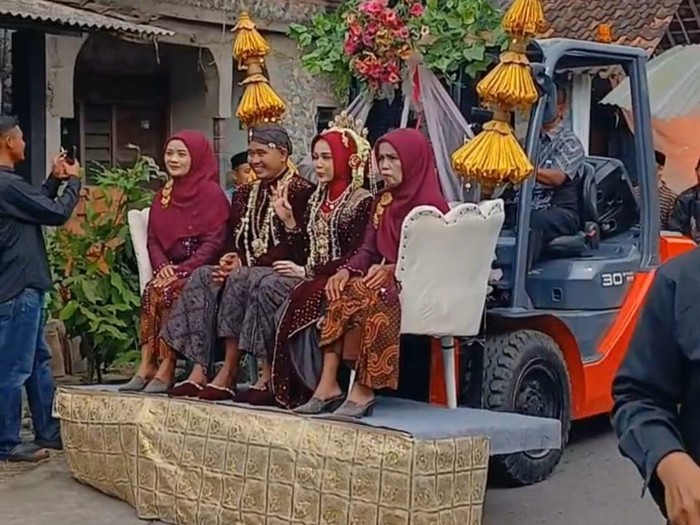 Arak-arakan pengantin naik forklift di Sedayu, Kecamatan Muntilan, Kabupaten Magelang, Minggu (22/6/2024).