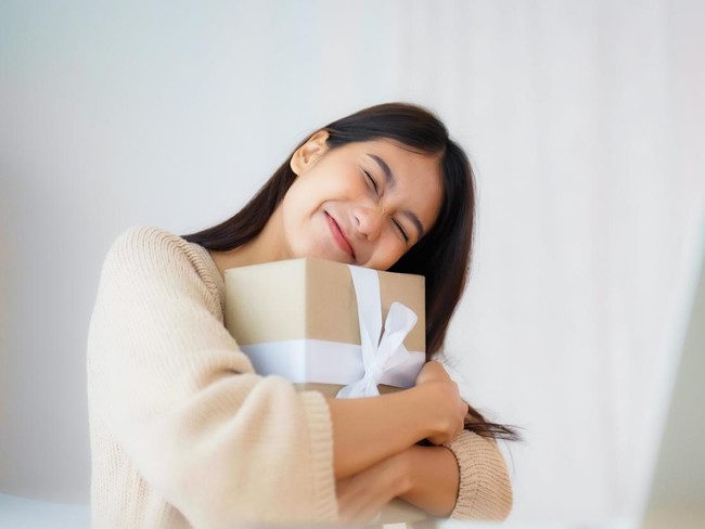 Young asian woman using computer laptop at home. Female showing gift box while on video conversation with friend. Happy birthday, Happy new year, Thanksgiving