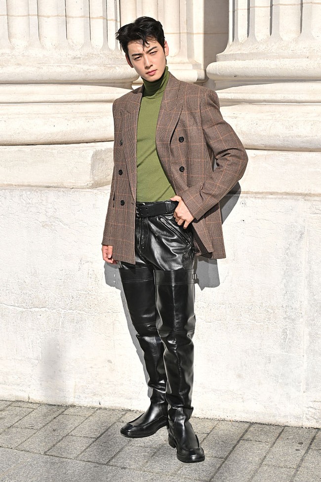 Cha Eun Woo menghadiri Paris Fashion Week 2025 sebagai global ambassador Saint Laurent. Bintang drama Korea True Beauty itu menunjukkan sisi barunya kepada penggemar, tampil berbalut turtleneck hijau dan coat berwarna coklat. Atasannya dipadukan dengan bawahan leather pants dan sepatu boots serasi setinggi pahanya. Foto: Getty Images