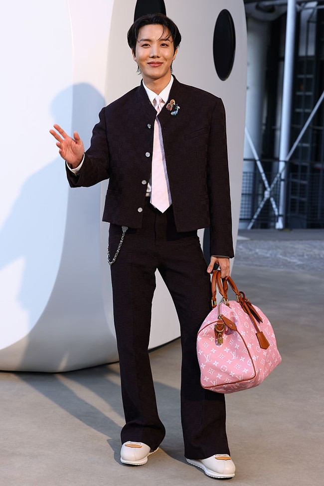 J-Hope BTS tampil standout saat tiba di peragaan busana Louis Vuitton. Personel grup KPop BTS itu mengenakan setelan jaket dan celana berwarna maroon. Tak lupa menambahkan sentuhan warna pink dari dasi dan tasnya sebagai fashion statement. Foto: Getty Images