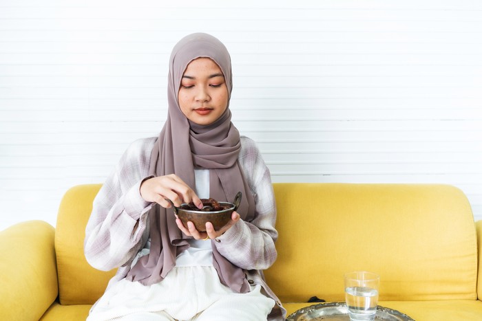Young muslim woman eating date to break fast at home