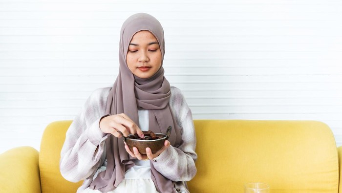 Young muslim woman eating date to break fast at home