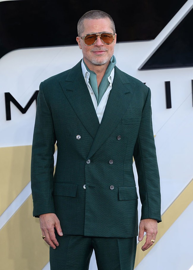 Brad Pitt tampil necis dengan setelan tuxedo warna emerald green. Aktor 61 tahun ini memadukan jas dengan kemeja putih dan syal berwarna senada. Foto: WireImage/Karwai Tang