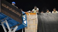 Sejumlah petugas profesional menaikkan kain hitam berhiaskan kaligrafi emas untuk mengganti Kiswa, penutup suci Kabah di Masjidil Haram, Arab Saudi, Rabu (25/6/2025). REUTERS/SAUDI PRESS AGENCY