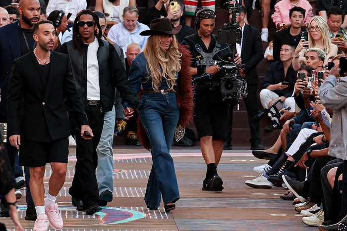 PARIS, FRANCE - JUNE 24: Jay-Z wears a black leather jacket with Louis Vuitton monogram logo print, a white t-shirt, a belt, black wide-leg pants, black leather pointed shoes ; Beyoncé Knowles / Beyonce wears a cowboy hat, a burgundy faux fur fluff coat on one shoulder, a blue denim jacket, blue flared denim pants / jeans, during the Louis Vuitton Menswear Spring/Summer 2026 show as part of Paris Fashion Week on June 24, 2025 in Paris, France. (Photo by Edward Berthelot/Getty Images)