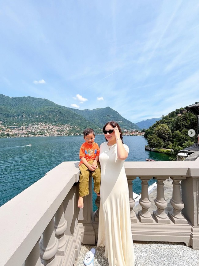 Berpose bersama Rayyanza dengan latar belakang danau di Italia, Nagita tampil dengan dress putih panjang dari brand Swedia, Toteme. Menurut Instagram fanpage Nagita Slavita, dress tersebut merupakan Fluid Jersey Maxi T-shirt Dress dan dijual seharga Rp 9,7 juta. Foto: Dok. Instagram RaffiNagita