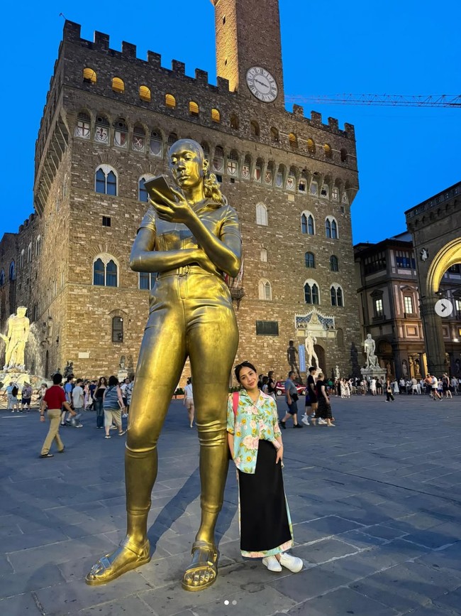 Berpose bersama patung di Italia, Nagita tampil dengan kemeja bunga dari brand Moschino. Kemeja bunga berwarna biru dengan motif smiley itu harganya di situs resmi Moschino mencapai Rp 14,5 juta. Foto: Dok. Instagram RaffiNagita