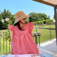 Nagita Slavina menikmati liburannya di Italia dengan berpose di sebuah kafe dengan latar taman bunga yang cantik. Nagita tampil dengan mini dress merah kotak-kotak dari brand asal Denmark, Ganni. Foto: Dok. Instagram RaffiNagita