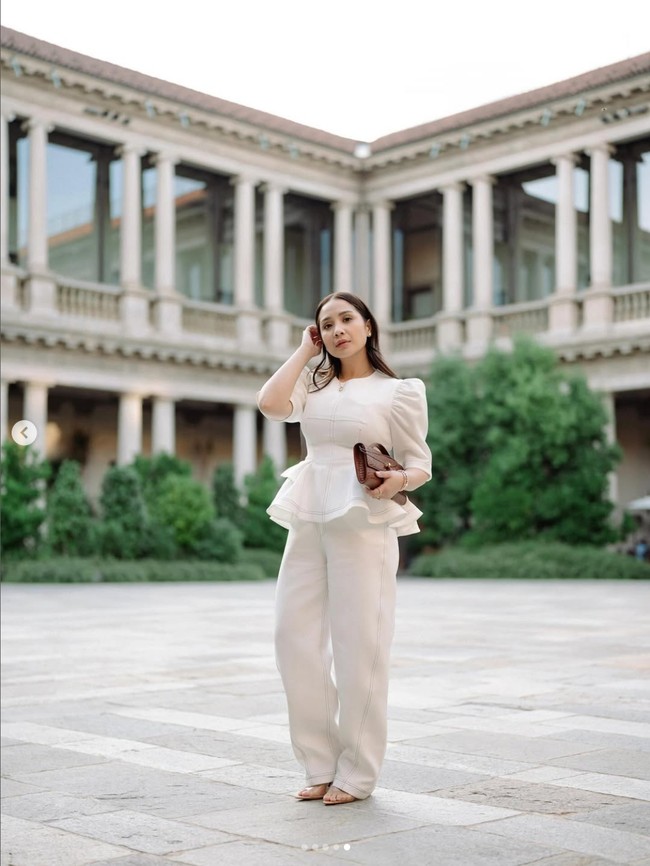 Saat liburan di Italia, Nagita Slavina tak lupa memakai busana dari brandnya sendiri Nagitaslavina.co. Busana serba putih itu dipadukannya dengan clutch Bottega Veneta seharga Rp 287 juta. Foto: Dok. Instagram RaffiNagita
