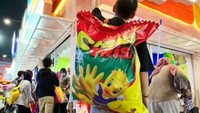 TikToker Steven Wang tak ingin ketinggalan berburu makanan berukuran besar di PRJ. Ia menggendong chiki rasa jagung bakar yang hanya tersedia 2 buah dalam sehari. Foto: TikTok/stevenwang