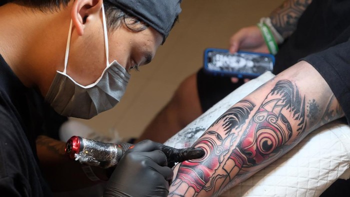 Seniman tato merajah punggung peserta saat kontes tato pada Denpasar Tattoo Fest 2025 di Gedung Dharma Negara Alaya, Denpasar, Bali, Jumat (27/6/2025). Denpasar Tattoo Fest 2025 yang digelar 27-28 Juni 2025 tersebut diikuti sebanyak 82 peserta kontes tato untuk merayakan dan mempromosikan seni tato sebagai bentuk ekspresi kreatif, serta untuk memajukan industri tato di Bali dan mengubah pandangan negatif masyarakat terhadap seni tato. ANTARA FOTO/Nyoman Hendra Wibowo/rwa.