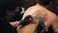 Seniman tato merajah punggung peserta saat kontes tato pada Denpasar Tattoo Fest 2025 di Gedung Dharma Negara Alaya, Denpasar, Bali, Jumat (27/6/2025). Foto: ANTARA FOTO/NYOMAN HENDRA WIBOWO