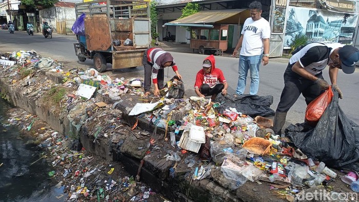 Petugas membersihkan sampah berserakan yang meluber ke got di Jalan Mallengkeri, Makassar.