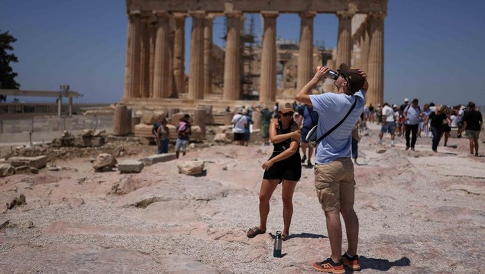 Athena Kepanasan! Turis Berlindung di Tengah Suhu Ekstrem Gelombang panas ekstrem melanda Athena, Yunani, pada Jumat (27/6/2025), memaksa warga dan wisatawan mencari cara bertahan di tengah suhu yang membakar. REUTERS/Stelios Misinas
