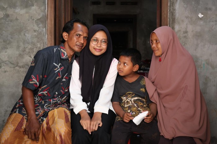 Putri Khasanah penerima beasiswa UKT Pendidikan Unggul Bersubsidi subsidi 100 persen dari UGM diapit orang tua dan adiknya.