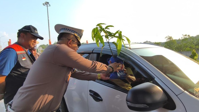Ditlantas Polda Riau mengdukasi kamseltibcarlantas kepada pengendara di momen HUT Bhayangakra sambil membagikan pohon, pada Jumat (27/6/2025).