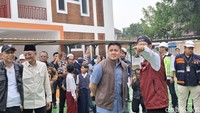 Tampak Gus Ipul menjelaskan ke Seskab Teddy di tengah lapangan Sekolah Rakyat, di bawah gerimis hujan.  Foto: Nograhany Widhi Koesmawardhani/detikEdu
