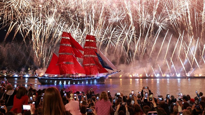 Demi Wisuda Siswa, Kapal Bersail Merah Rusia Muncul Setahun Sekali Spectators watch fireworks exploding in the sky and the brig
