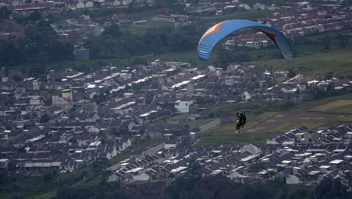 Wisatawan bersama pilot paralayang mengudara di atas kawasan Cihampelas, Kabupaten Bandung Barat, Jawa Barat, Senin (30/6/2025). Pariwisata olahraga (sport tourism) yang dikelola oleh Paralayang Bandung Raya tersebut menawarkan paket wisata paralayang dengan terbang dari ketinggian 1.080 meter di atas permukaan laut (mdpl) sekaligus mengenalkan potensi pariwisata di daerah itu. ANTARA FOTO/Abdan Syakura