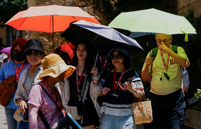 Tourists protect themselves from the hot sun with umbrellas during the first summer heatwave in Seville, southern Spain June 29, 2025. REUTERS/Marcelo del Pozo