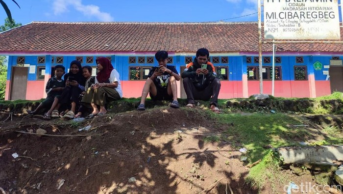 Anak anak di kampung susah sinyal berkumpul di lapangan untuk mencari jaringan Internet