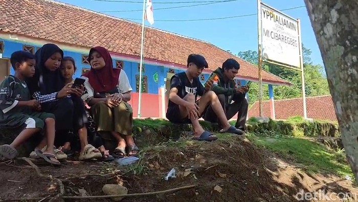 Anak anak di kampung susah sinyal berkumpul di lapangan untuk mencari jaringan Internet