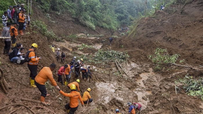 Tim SAR dibantu relawan dan warga membersihkan material tanah longsor saat pencarian korban yang tertimbun tanah longsor di Desa Tenjowaringin, Kecamatan Salawu, Kabupaten Tasikmalaya, Jawa Barat, Selasa (1/7/2025). Tebing setinggi 250 meter dengan luas panjang material longsoran 800 meter yang menutupi lahan pesawahan milik warga itu, mengakibatkan dua orang petani tertimbun tanah longsor pada Minggu (29/6/2025) siang. ANTARA FOTO/Adeng Bustomi/foc.