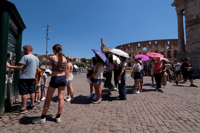 Tourists stand in front of a cooling fan installed outside the Colosseum in during the heatwave in Rome, Italy, June 30, 2025. REUTERS/Remo Casilli     TPX IMAGES OF THE DAY