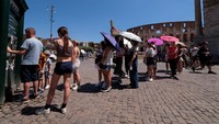 Wisatawan antre mengambil air segar di dekat Colosseum saat gelombang panas melanda Roma, Italia, Senin (30/6/2025). Warga diminta membatasi aktivitas luar ruang pada siang hari. (REUTERS/Remo Casilli)  