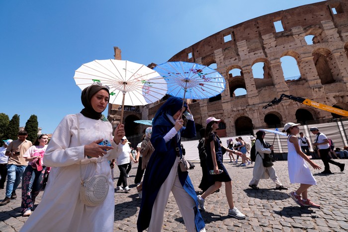 Tourists stand in front of a cooling fan installed outside the Colosseum in during the heatwave in Rome, Italy, June 30, 2025. REUTERS/Remo Casilli     TPX IMAGES OF THE DAY