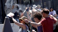 Wisatawan berdiri di depan kipas pendingin yang dipasang di luar Colosseum saat gelombang panas melanda Roma, Italia, Senin (30/6/2025). Italia dilanda gelombang panas ekstrem pada akhir Juni 2025. (REUTERS/Remo Casilli)  