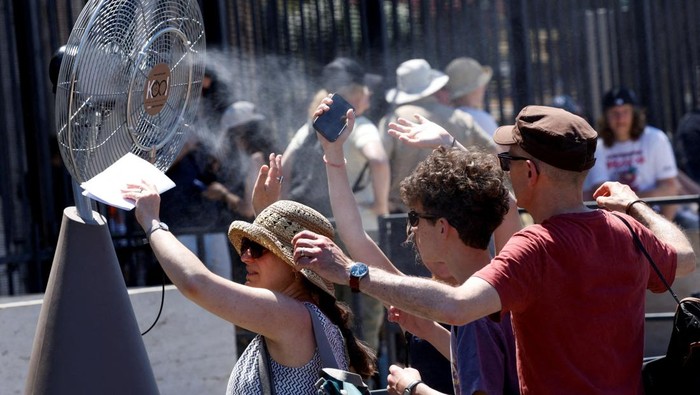 'Neraka Bocor' di Roma, Wisatawan Kewalahan Tourists stand in front of a cooling fan installed outside the Colosseum in during the heatwave in Rome, Italy, June 30, 2025. REUTERS/Remo Casilli TPX IMAGES OF THE DAY