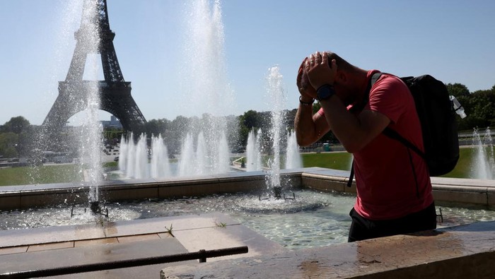 A tourist cools off in the Trocadero Fountain next to the Eiffel Tower as an early summer heatwave hits Paris, France, July 1, 2025. REUTERS/Tom Nicholson