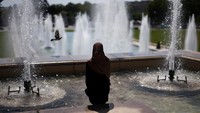 Turis menyejukkan diri di Air Mancur Trocadero. Puncak suhu panas diperkirakan terjadi pada hari Selasa, meskipun badan cuaca nasional Meteo France memperpanjang peringatan cuaca hingga hari Rabu juga. Foto: REUTERS/Tom Nicholson