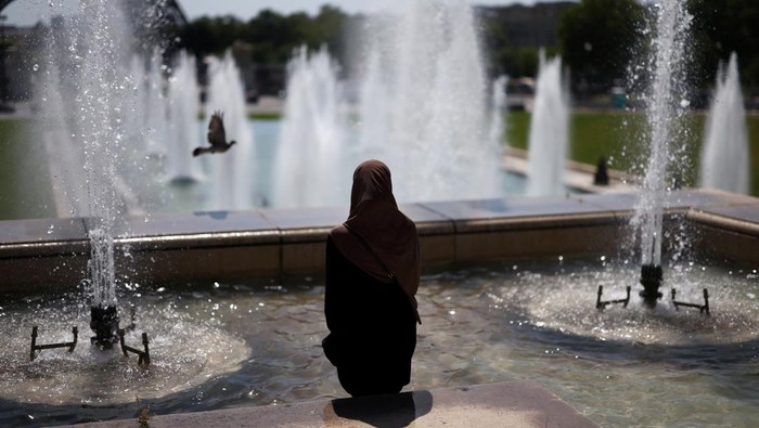 A tourist cools off in the Trocadero Fountain next to the Eiffel Tower as an early summer heatwave hits Paris, France, July 1, 2025. REUTERS/Tom Nicholson
