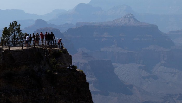 Mijung Cha, 49, and her daughter, Hyen Han, 12, standing behind Cha's son, Taein Han, 10, and her husband Gibaeg Han, 61, of Seoul, South Korea, listen as National Park Seasonal Interpretation Ranger Jessica Borders, 24, leads a fossil walk program on the south rim of the Grand Canyon National Park in Grand Canyon Village, Arizona, U.S. June 29, 2025. REUTERS/Kaylee Greenlee