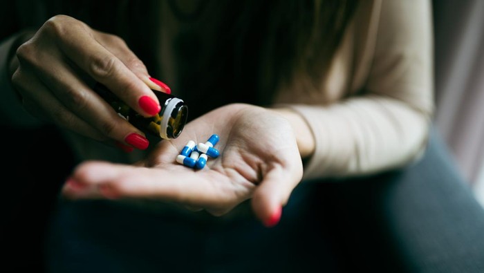 Close up of female hand preparing and holding medical pills from pack.